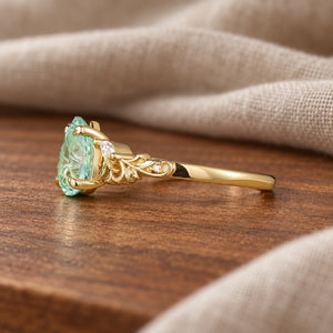 Rene olive-branch inspired green sapphire engagement ring side view on warm walnut tabletop