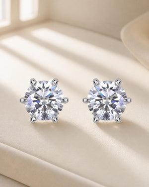 Round six claw sparkle silver moissanite stud earrings on warm walnut