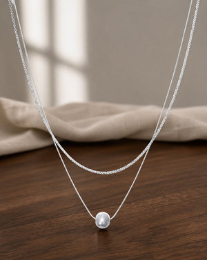 Silver Chatoyancy Ball Bead Layered Necklace on warm walnut surface
