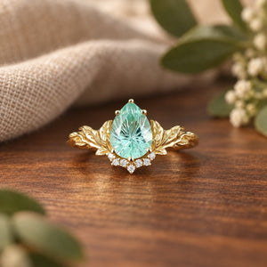 Sparkle Cut green sapphire leaf-inspired engagement ring on warm walnut tabletop with natural linen