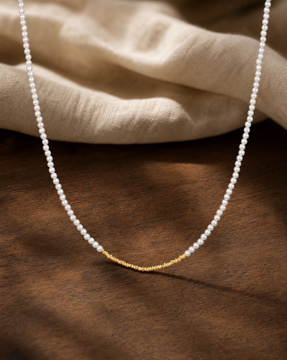 Minimal Mini Gold Beaded Pearl Choker Necklace on warm walnut surface