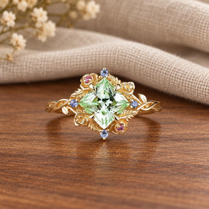 Princess-cut green sapphire whimsical nature-inspired engagement ring on warm walnut tabletop