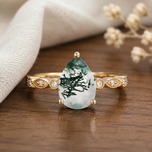 Unique inspired pear-cut moss agate engagement ring on a natural walnut tabletop