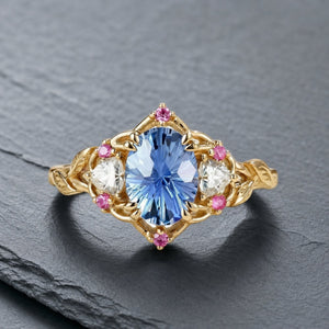 Audrey three-stone sapphire engagement ring on warm botanical stone