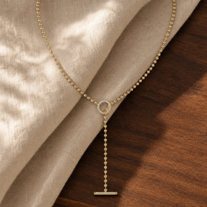 Classic gold beaded bar lariat toggle necklace on warm walnut