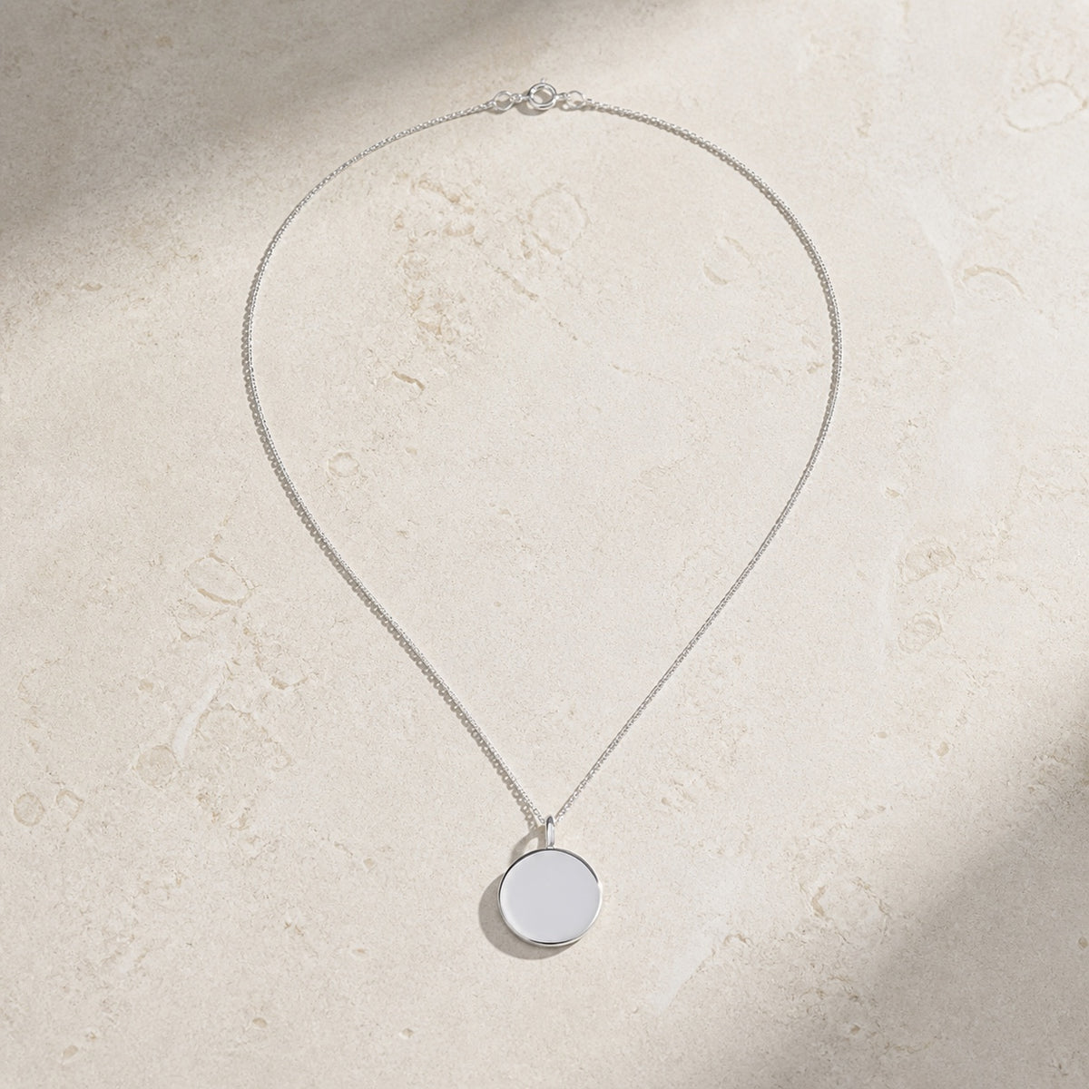 Sterling silver round pendant necklace on pale stone