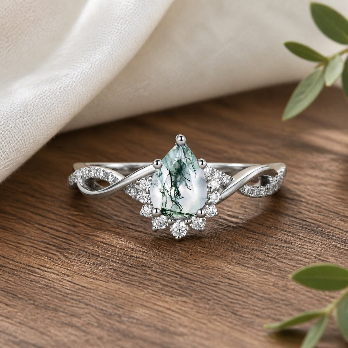 Barbara's Grove Pear Moss Agate Infinity Engagement Ring on natural walnut tabletop