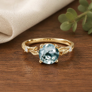 Aurelia's Leaflet Round Cut Moss Agate Leafy Engagement Ring on natural walnut tabletop