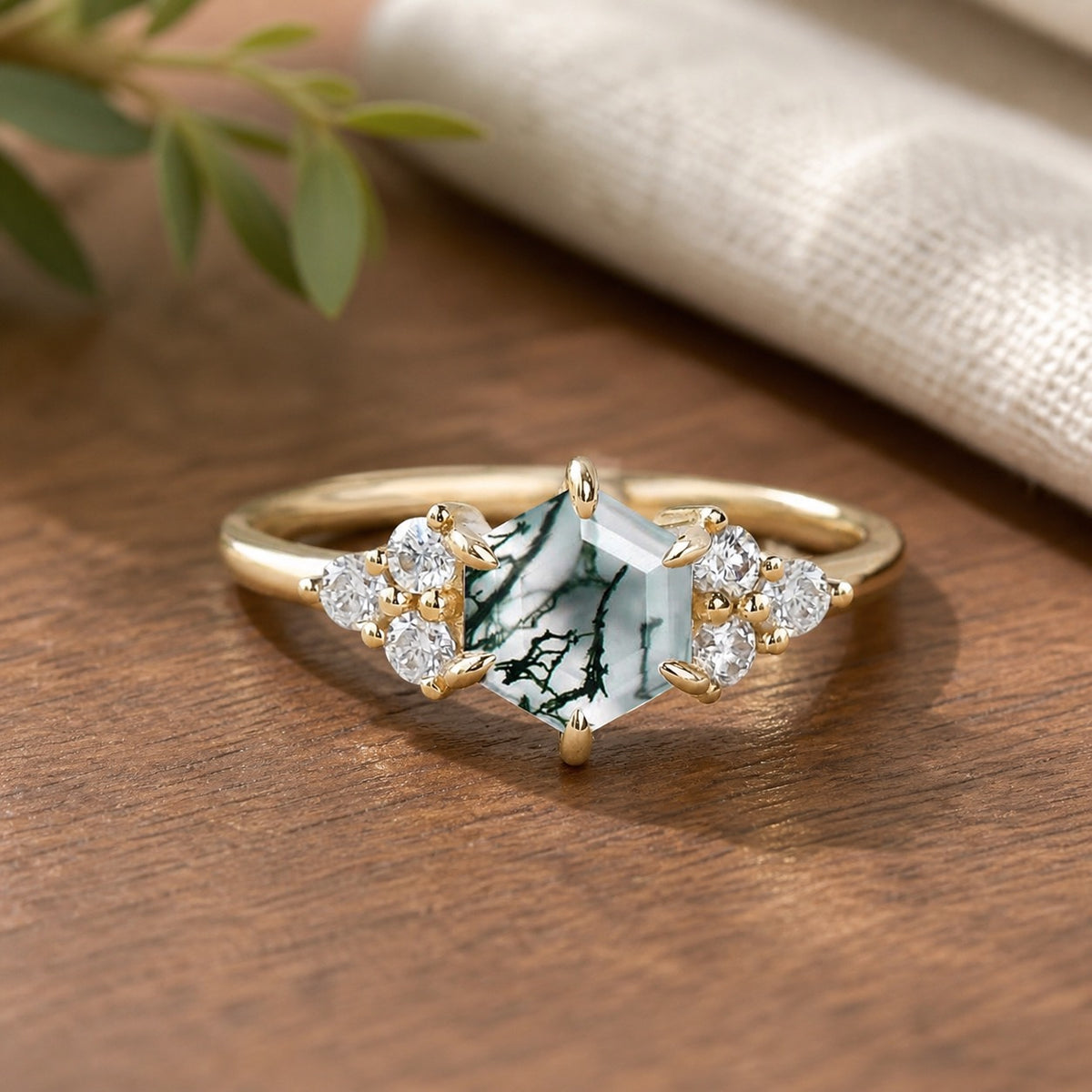 Sylvie’s Hexagon moss agate three-stone cluster engagement ring on a natural walnut tabletop