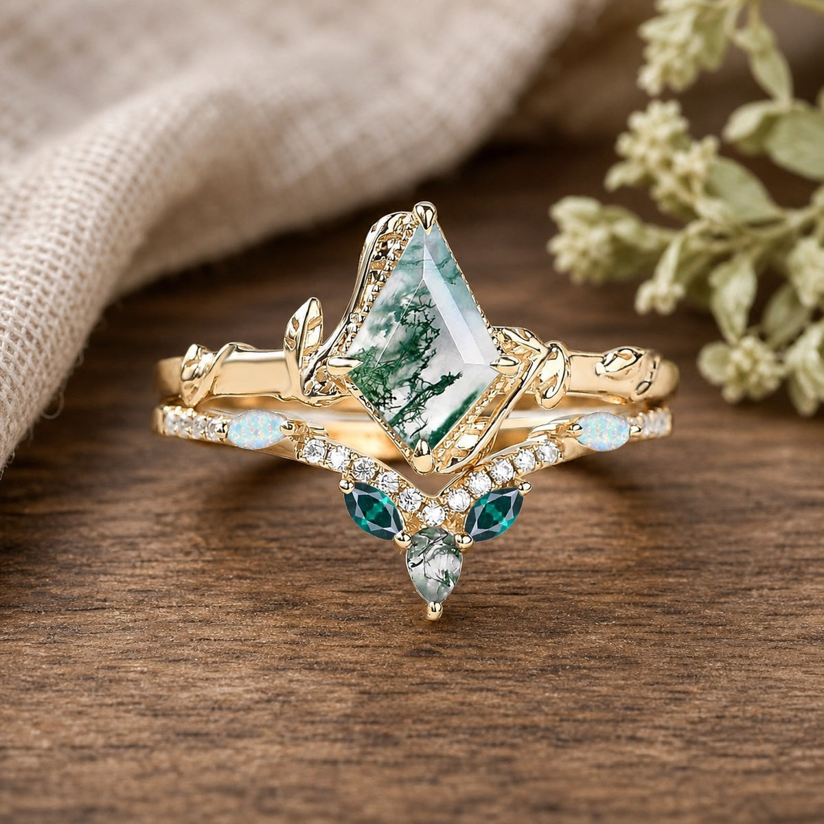 Seraphina’s Trilogy kite-cut moss agate, opal and emerald foliage bridal duo on a warm walnut tabletop