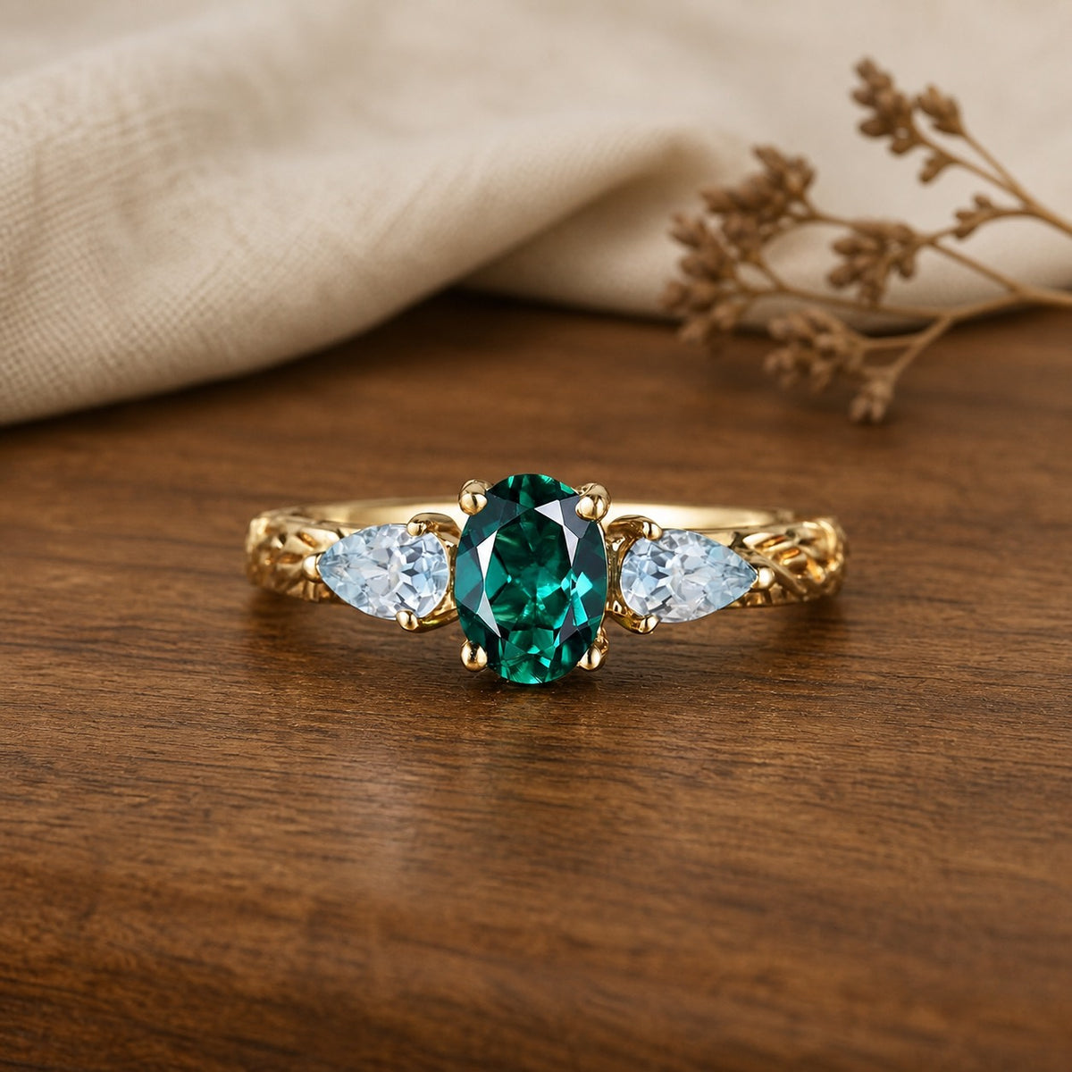 Oval emerald and aquamarine cluster engagement ring on a warm walnut tabletop