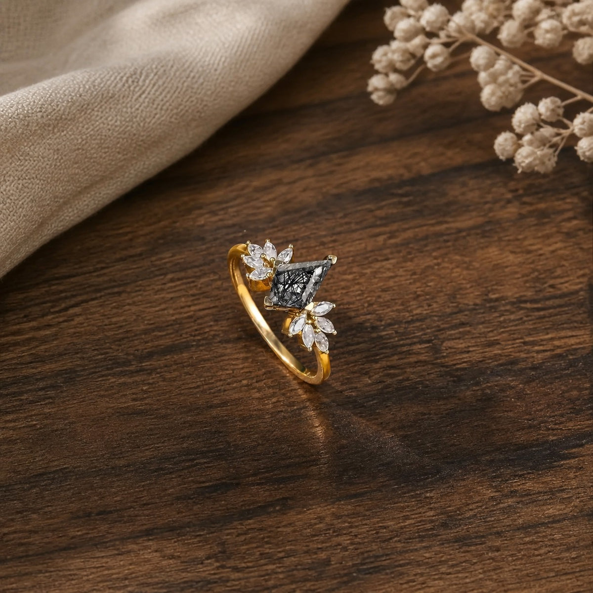Unique kite-shaped black rutilated quartz engagement ring on a warm walnut tabletop