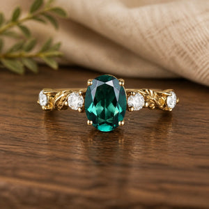 Oval emerald leaf engraved engagement ring on a warm walnut tabletop