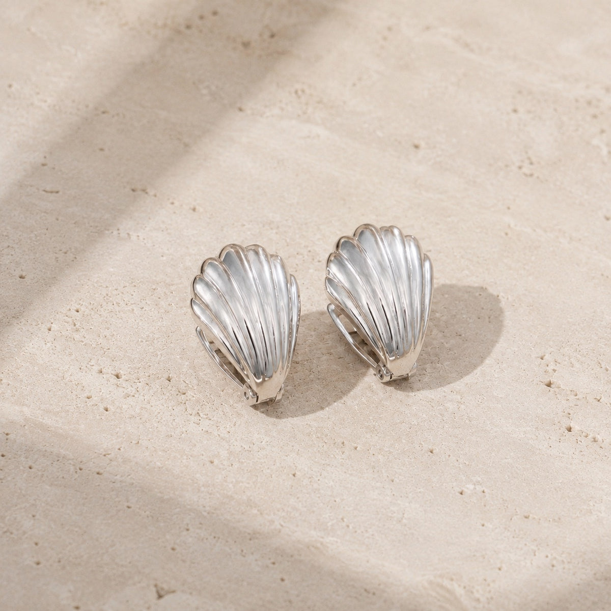 Silver frosted shell huggie hoop earrings on pale stone