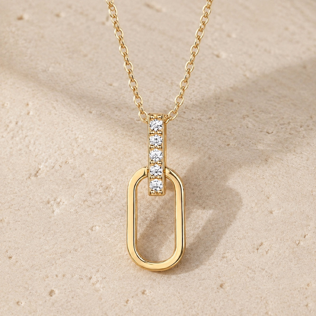 Gold oval-link moissanite pendant necklace on pale stone