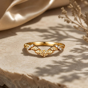 Curved rose-inspired moissanite wedding band on warm stone